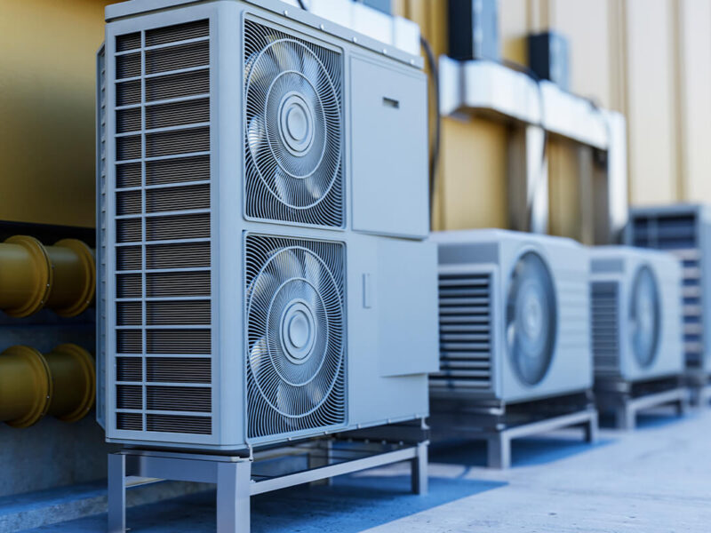 Graues Außengerät einer Klimaanlage mit zwei Ventilatoren auf einem stabilen Gestell.